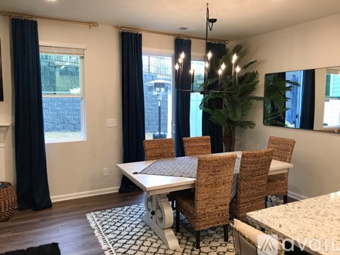A dining room with a white table and brown chairs.