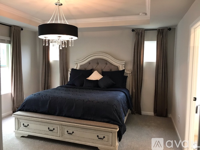 A bedroom with a large bed and a chandelier.