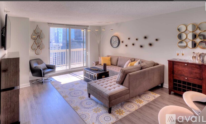 A living room with a grey couch, a black chair, a wooden cabinet, and a TV mounted on the wall.