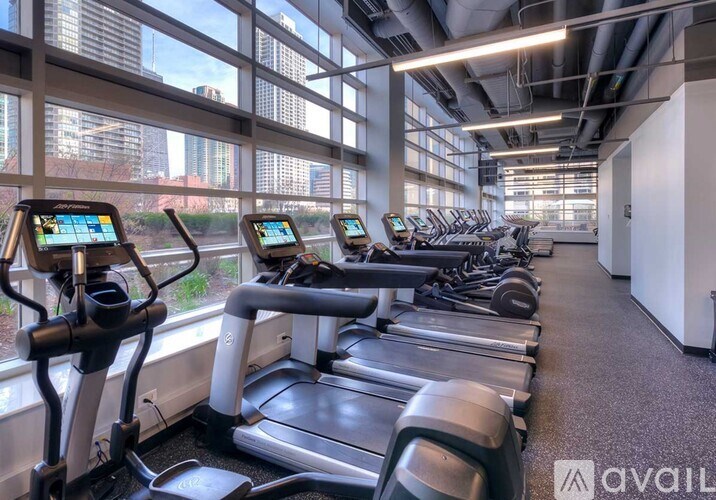 A gym with treadmills and a view of the city outside the windows.