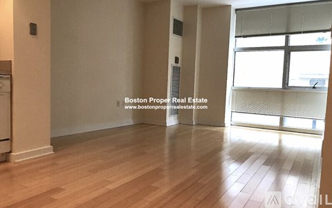 A room with wooden flooring and a window with blinds.