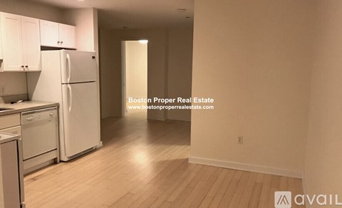 A kitchen with white appliances and wooden floors is available for rent.