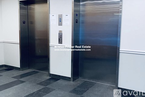 Two elevators in a building with a sign for Avail and a website address for a real estate company.