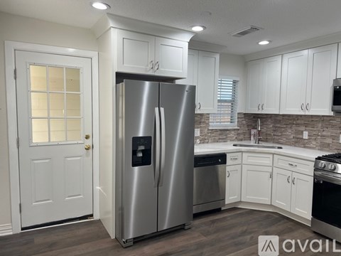 A modern kitchen with a stainless steel refrigerator and white cabinets.