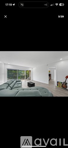 A modern living room with a green sofa and a guitar on the wall.