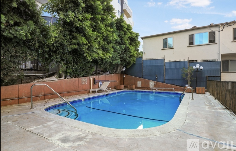 A small residential pool surrounded by a fence and trees.