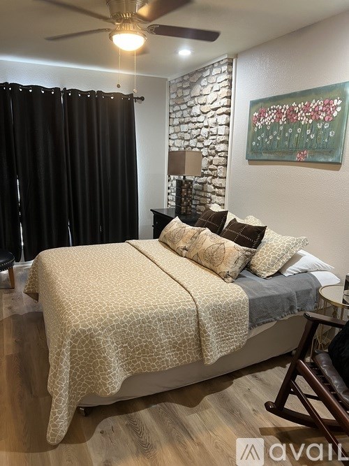 A bedroom with a bed covered in a patterned blanket and a painting on the wall.