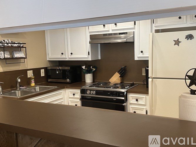 A kitchen with a black stove top oven and white cabinets.