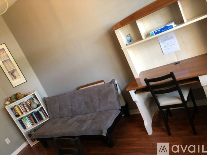 A living room with a grey couch, a wooden chair, and a white chair.