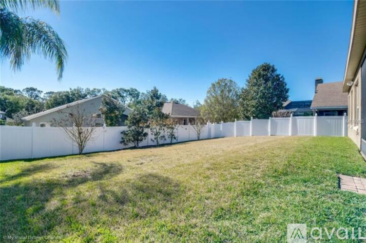 A white fence separates a grassy area from a building.