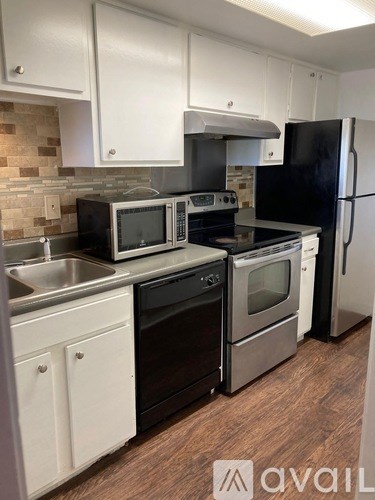 A kitchen with black appliances and white cabinets.