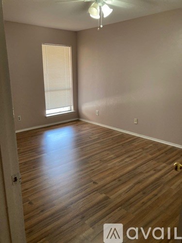 A room with wooden flooring and a window with blinds.