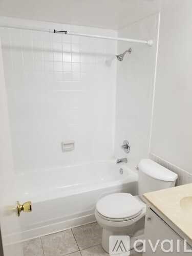 A white toilet sits next to a white bathtub in a bathroom.