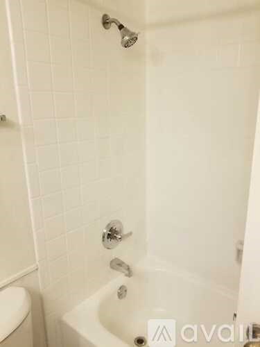 A white bathroom with a white tub and a white toilet.