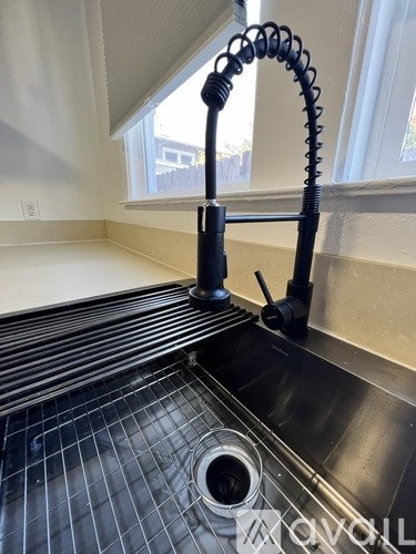 A black vacuum cleaner with a flexible hose is on a black tiled floor.