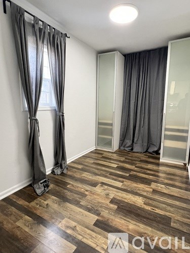 A room with wooden flooring and grey curtains.