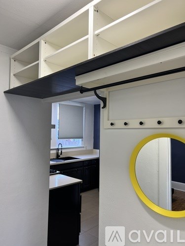 A kitchen with a white wall and a yellow framed mirror.