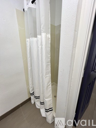 A white shower curtain with black stripes hangs on a white door.