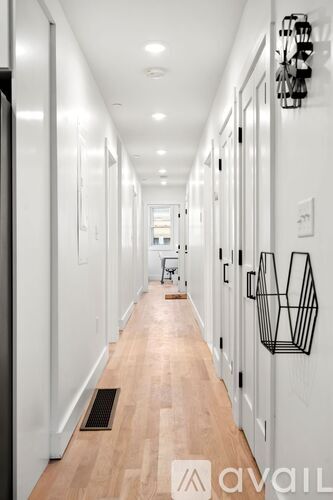 A long hallway with a wooden floor and white walls.