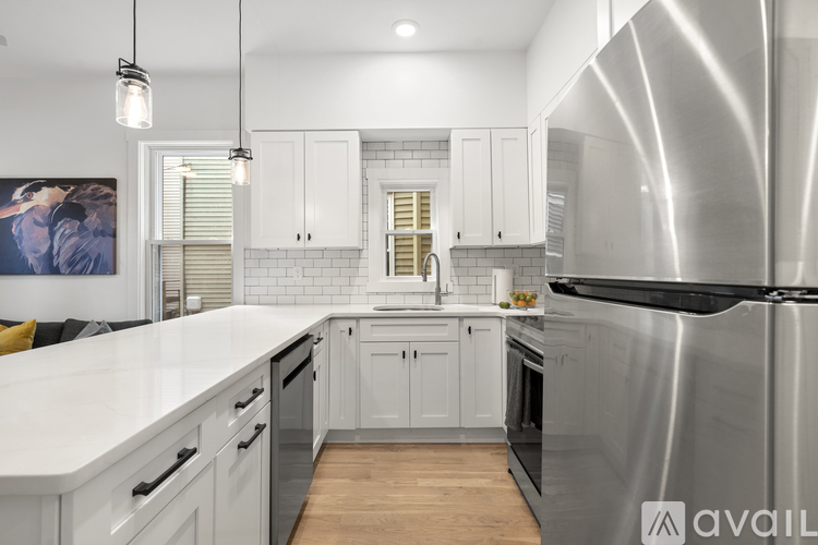 A modern kitchen with a large stainless steel refrigerator and white countertops.