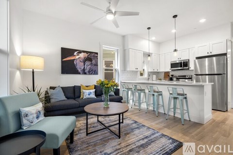 A living room with a grey couch and a coffee table with a vase of flowers on it.