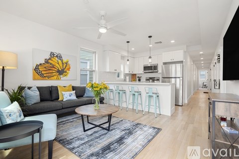 A living room with a grey couch, a coffee table, and a painting of a butterfly on the wall.