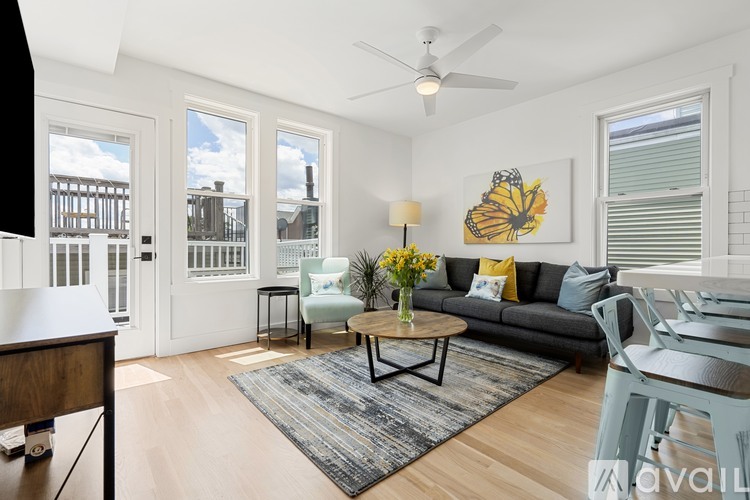 A living room with a grey couch, a coffee table, and a painting of a butterfly on the wall.