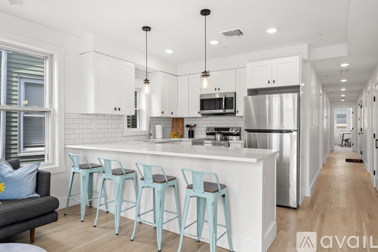 A kitchen with white cabinets and a bar area with blue stools.