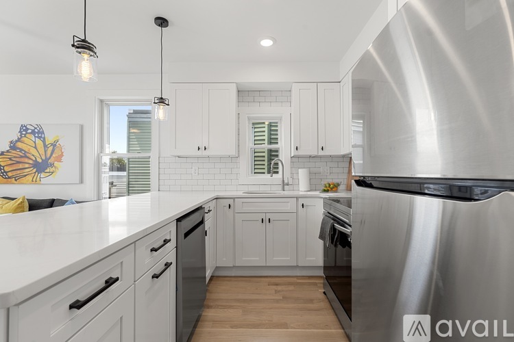 A modern kitchen with a stainless steel refrigerator and white countertops.