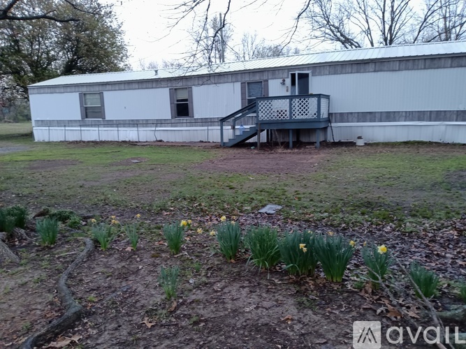 A white building with a deck and daffodils in the foreground.