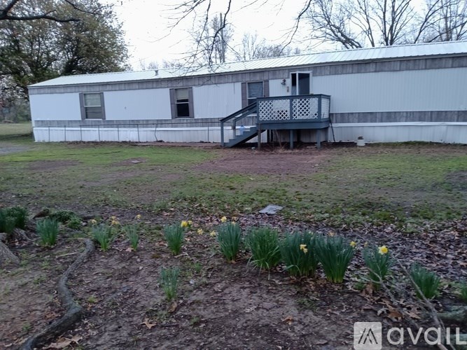 A white building with a deck and daffodils in the foreground.