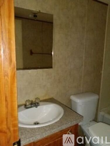 A bathroom with a sink, toilet and mirror.