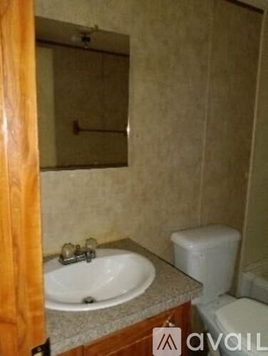 A bathroom with a sink, toilet and mirror.