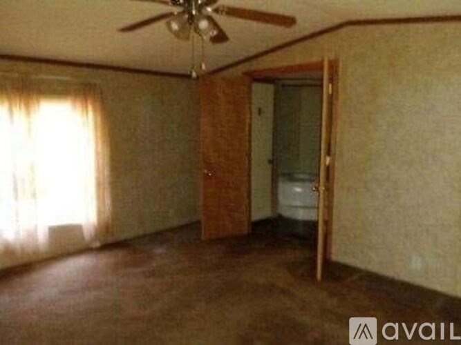A room with a ceiling fan and a door leading to another room.