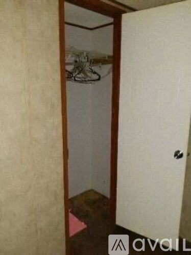 A hallway with a door on the right and a coat rack on the left.