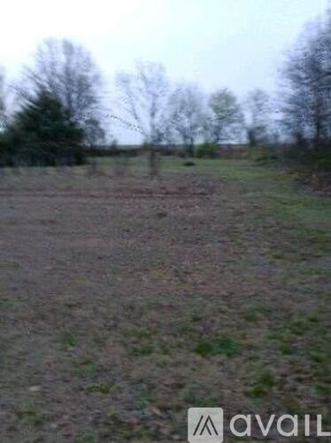 A field with trees in the background and a logo in the bottom right corner.