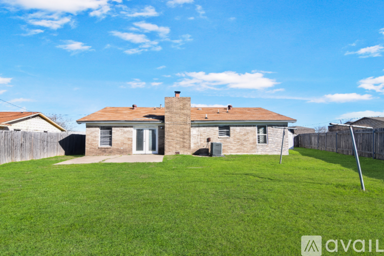 A house with a brown roof and a chimney is surrounded by a grassy yard.