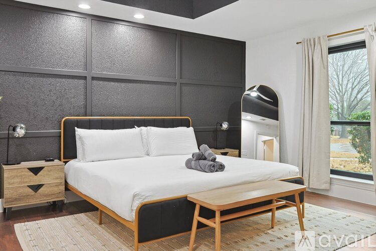 A bedroom with a large bed and a window overlooking a tree.