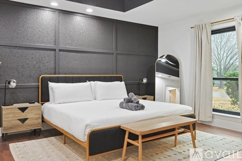 A bedroom with a large bed and a window overlooking a tree.