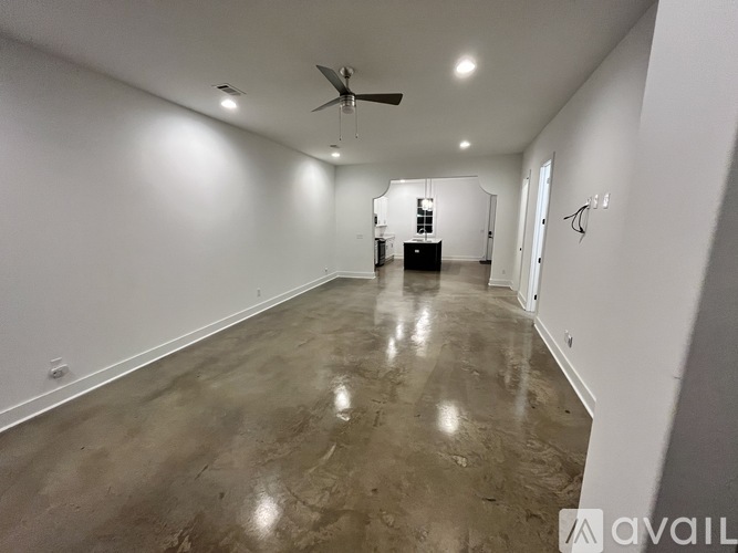 A spacious room with a ceiling fan and a concrete floor.