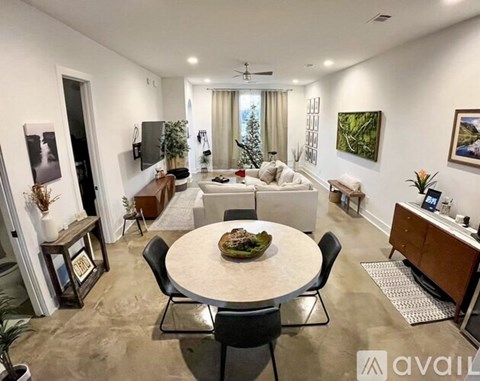 A living room with a dining table and chairs, a couch, and a television.