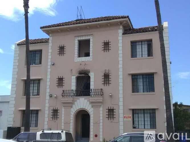 A beige building with a balcony and a car parked in front.