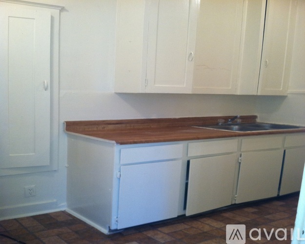 A kitchen with white cabinets and a wooden countertop.