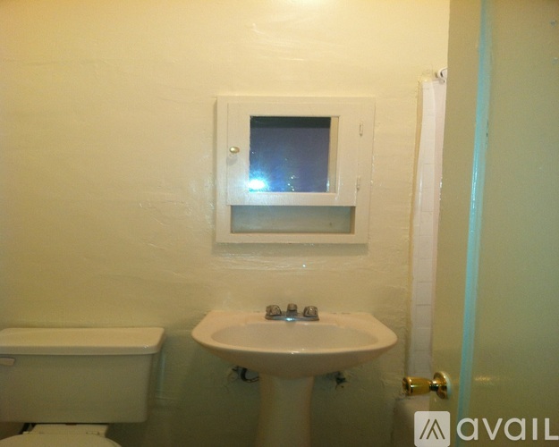 A bathroom with a toilet, sink and mirror.