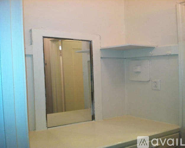 A mirrored wardrobe with a white door and a light switch on the wall.