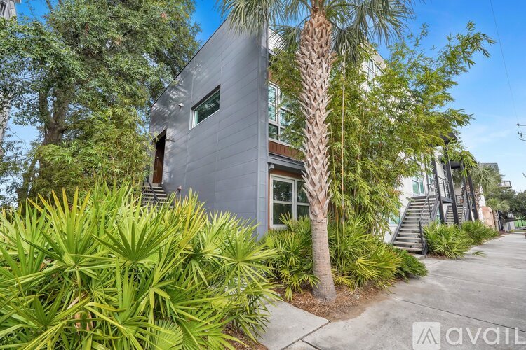 A modern house with a grey exterior and a palm tree in front.