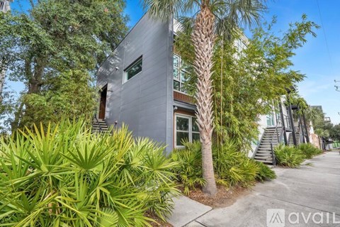 A modern house with a grey exterior and a palm tree in front.