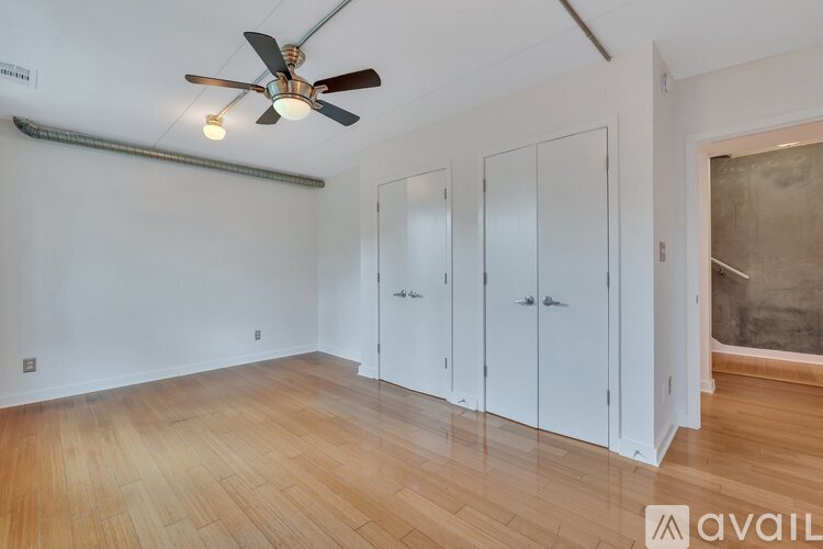 A room with a ceiling fan and three white doors.