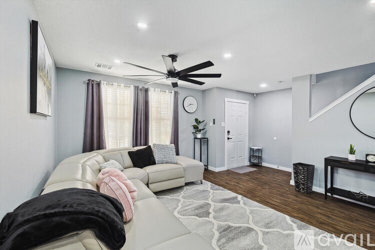 A living room with a white couch and a ceiling fan.