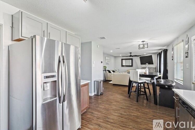 A kitchen with a refrigerator and a dining table.